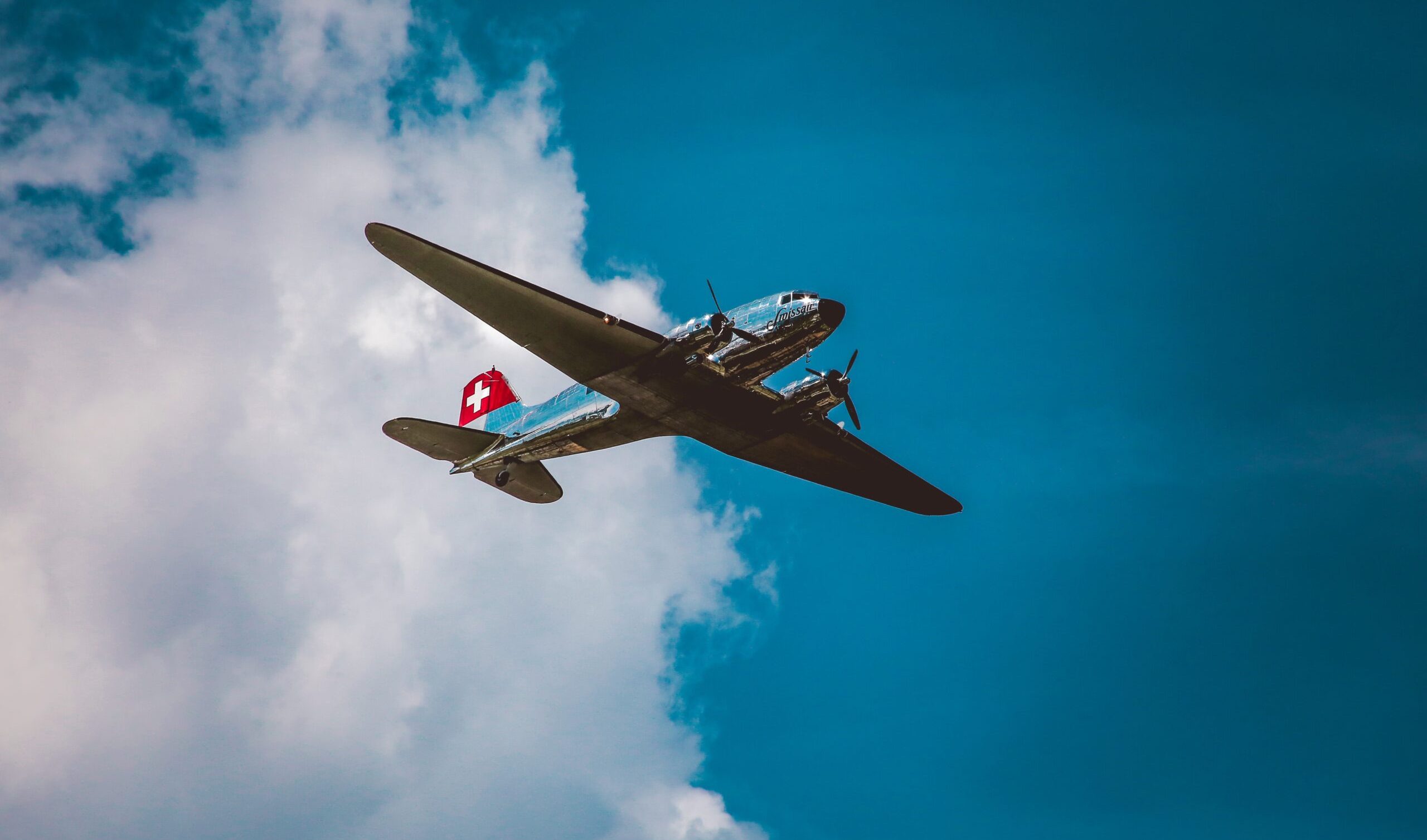 A horizontal low angle shot of a silver airplane under the beautiful cloudy sky